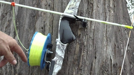 Finger pointing at a reel attached to a bow on wood