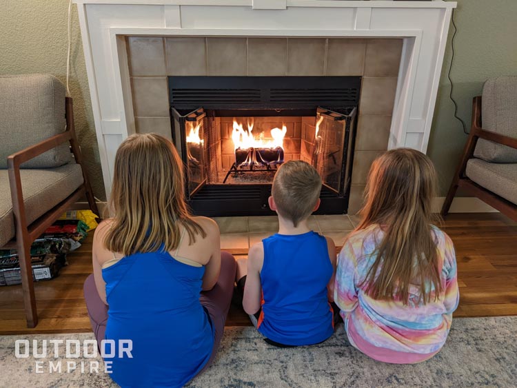Three kids sitting in front of a fireplace