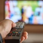 Man holding remote in front of tv