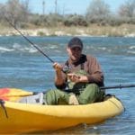 Man in river fishing in a kayak