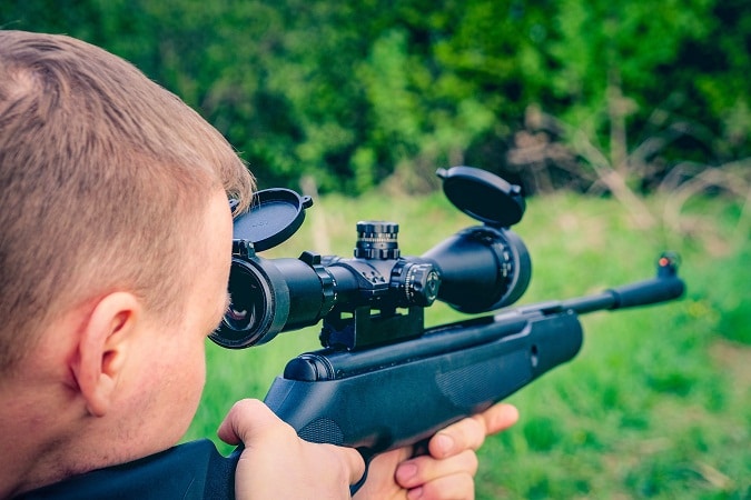 man looking through airgun scope