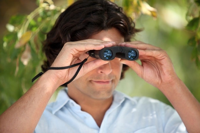 man looking through compact binocs