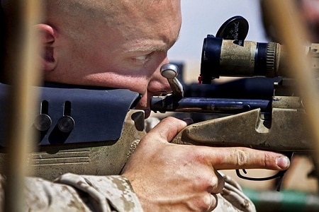 Man looking through rifle scope