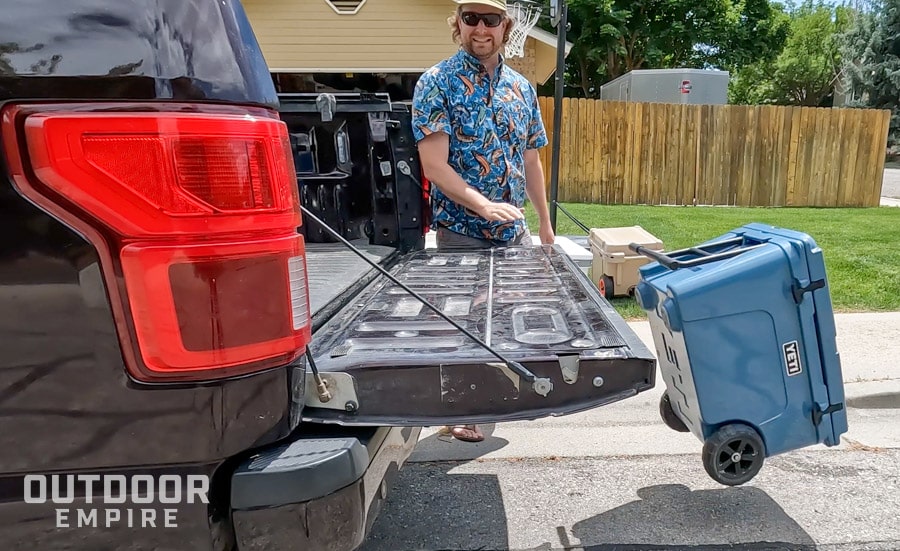 Yeti tundra haul cooler being pushed off truck tailgate with man grimacing